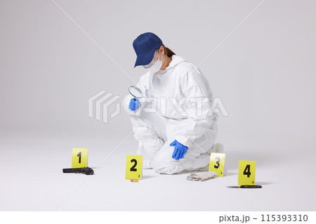 Evidence Marker A female researcher who checks evidence with a magnifying glass at the crime scene and at the incident site 115393310