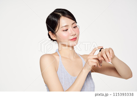 an Asian woman who applies foundation on the back of her hand an Asian woman who applies foundation on the back of her hand 115393338