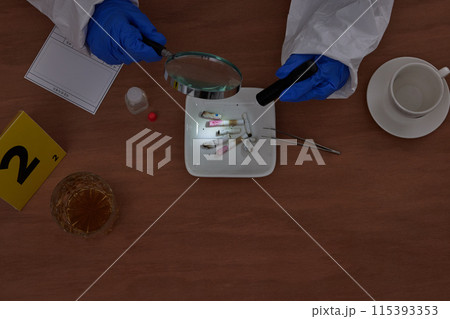 The hand of a CSI Scientific Investigation Unit researcher who identifies evidence with magnifying glasses and flashlights at crime and incident sites 115393353