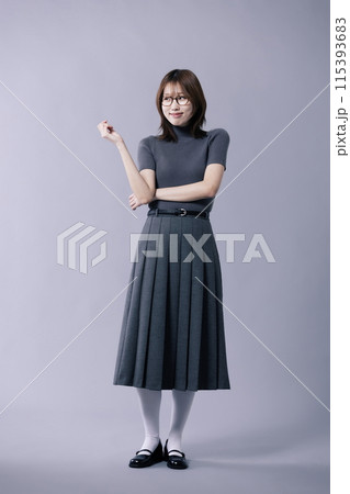A Korean woman in her 20s wearing glasses and a gray knit short sleeved shirt and pleated skirt 115393683