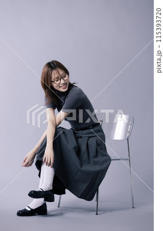 A Korean woman in her 20s who wears a geek look style and smiles sitting on a chair A Korean woman in her 20s who wears a geek look style and smiles sitting on a chair 115393720