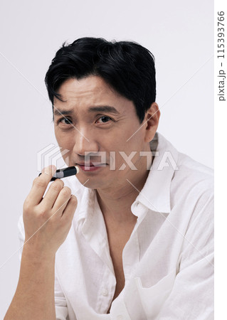 A middle aged man puts lip balm on his lips A middle aged man puts lip balm on his lips 115393766