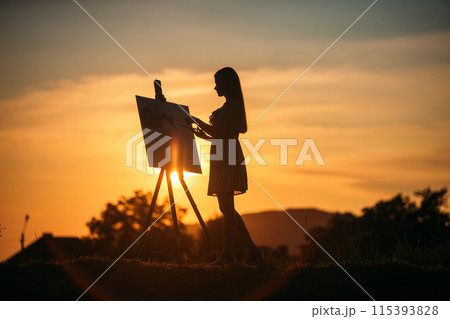 Silhouette of blonde girl paints a painting on the canvas.Palette with paints and spatula, summer sunny day Silhouette of blonde girl paints a painting on the canvas.Palette with paints and spatula, summer sunny day 115393828
