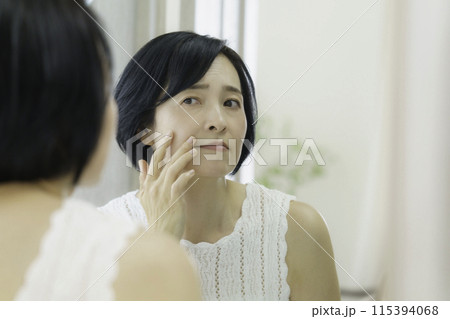 鏡を見て皺を気にするミドルエイジの女性 鏡を見て皺を気にするミドルエイジの女性 115394068