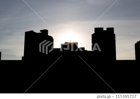 City skyline silhouette with sun shining through clouds City skyline silhouette with sun shining through clouds 115395717