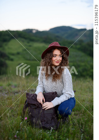 Young tourist woman traveller with backpack walking in nature. Active hiker on trail in mountains enjoying sunset. 115396179