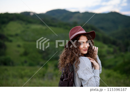 Young tourist woman traveller with backpack walking in nature. Active hiker on trail in mountains enjoying sunset. 115396187