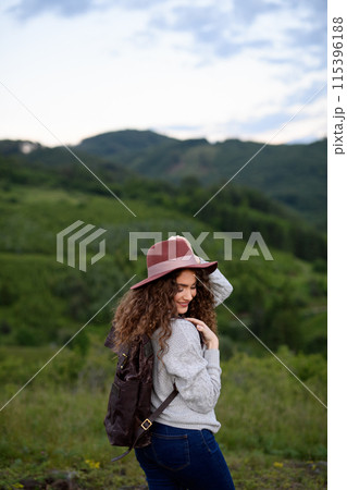 Young tourist woman traveller with backpack walking in nature. Active hiker on trail in mountains enjoying sunset. 115396188