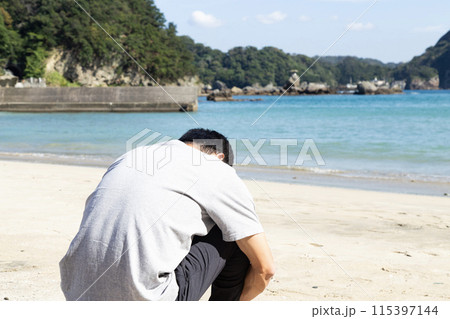 海で俯く男性の後ろ姿 115397144