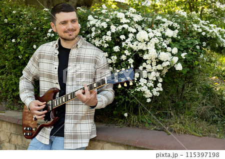 Attractive young guy playing guitar in the park Attractive young guy playing guitar in the park 115397198