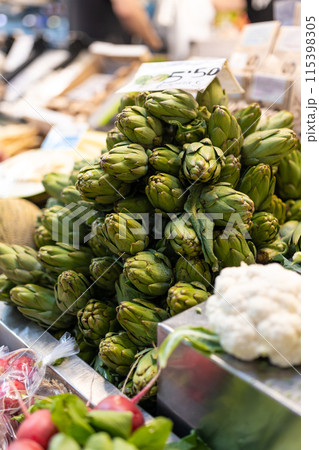 Fresh green artichokes in a market. Fruit and vegetable stand, view of artichokes. Counters with fresh vegetables 115398305
