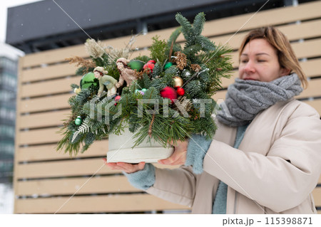 Woman Holding Potted Plant With Christmas Decorations Woman Holding Potted Plant With Christmas Decorations 115398871