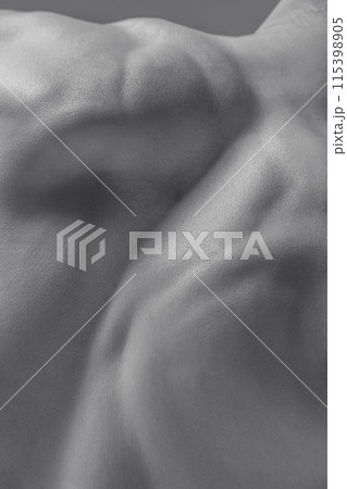 Black and white photograph of muscular male shirtless body in dynamic pose, showing strength and flexibility in human anatomy. 115398905