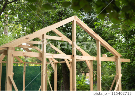 Construction of a large wood greenhouse in garden. Wooden domestic greenhouse for growing vegetables or flowers. 115402713