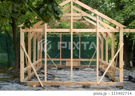 Construction of a large wood greenhouse in garden. Wooden domestic greenhouse for growing vegetables or flowers. 115402714