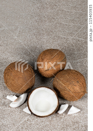 Whole coconuts and half a coconut on a blue and gray background close-up Whole coconuts and half a coconut on a blue and gray background close-up 115403935