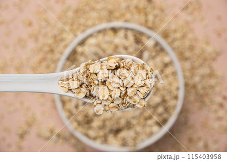 Dry uncooked oat flakes in a spoon top view 115403958