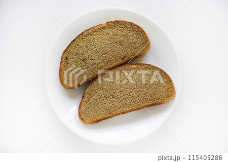 Two pieces of rye bread on a white plate. 115405286