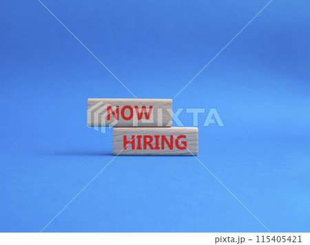 Now Hiring symbol. Concept word Now Hiring on wooden blocks. Beautiful blue background. Business and Now Hiring concept. Copy space 115405421