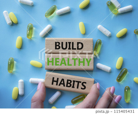 Healthy habits symbol. Concept word Build Healthy habits on wooden blocks. Doctor health. Beautiful blue background with pills. Healthy lifestyle and Healthy habits concept. Copy space 115405431