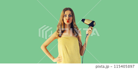 Beautiful young woman drying wet hair in wrapped bath towel after taking shower on green background Beautiful young woman drying wet hair in wrapped bath towel after taking shower on green background 115405897