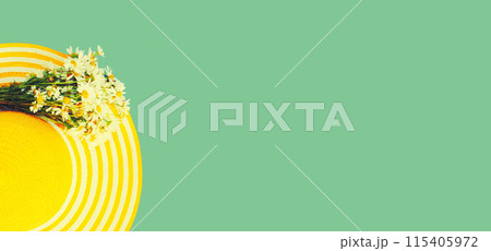 Summer yellow straw hat with chamomile flowers on green background, copy space for advertising text 115405972