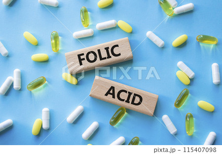 Folic acid symbol. Wooden blocks with words Folic acid. Beautiful blue background with pills. Medicine and Folic acid concept. Copy space. 115407098