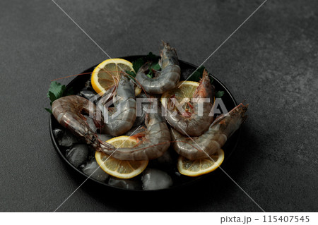Large King prawns on lemon slices and ice. Black plate. Black background Large King prawns on lemon slices and ice. Black plate. Black background 115407545