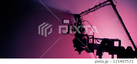 Professional video shoot studio. Behind the scenes of video commercial production shooting set. Silhouette of camera and equipment in studio. Making of online film advertising on set. Selective focus. 115407572