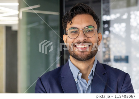 Portrait of a confident young professional smiling indoors in a modern office. Perfect for business, corporate, and workplace concepts. 115408067
