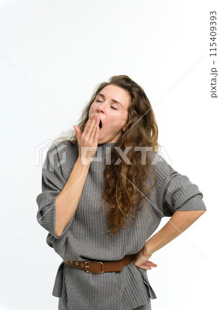 A young woman yawns covering her mouth with her hand. A young woman yawns covering her mouth with her hand. 115409393