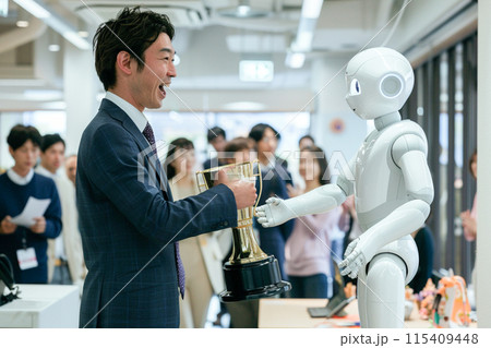 トロフィーを授与されるアンドロイドと自分ごとのように喜んでいる上司_1 115409448