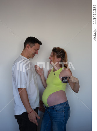 Expecting parents eagerly await their baby's arrival, holding the first ultrasound 115411383