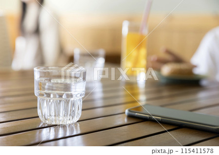 カフェの使い込まれた水用グラスとスマホ 115411578
