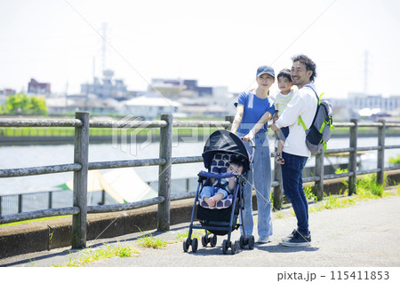 川の土手をベビーカーを押しながら歩く親子　 115411853