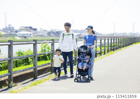 川の土手をベビーカーを押しながら歩く親子 川の土手をベビーカーを押しながら歩く親子 115411859