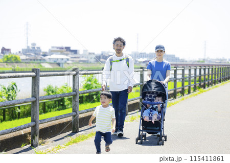川の土手をベビーカーを押しながら歩く親子　 115411861