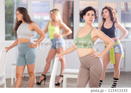 Group of girls unleash their energy and dance passionately near a chair in high heels in a dance studio. His powerful moves combined with elegance of high heels Group of girls unleash their energy and dance passionately near a chair in high heels in a dance studio. His powerful moves combined with elegance of high heels 115413335