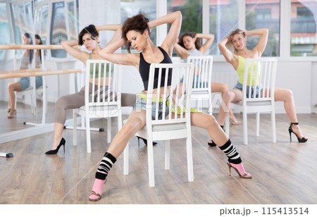 Group of women in high heels rehearsing dance while sitting on chair Group of women in high heels rehearsing dance while sitting on chair 115413514