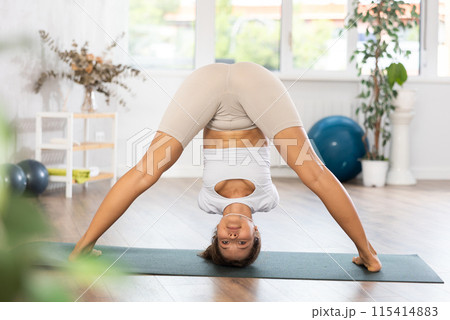 Woman exercising warrior one pose during yoga training in gym 115414883