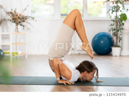 Experienced girl fitness club teacher performs scorpio asana, vrishchikasana 115414970