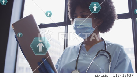 Image of media icons over african american female doctor wearing face mask Image of media icons over african american female doctor wearing face mask 115415637