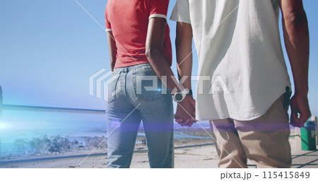 Image of light moving over midsection of couple walking by beach holding hands 115415849