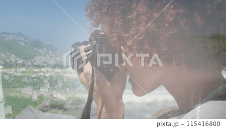Image of african american woman using camera, over cityscape 115416800