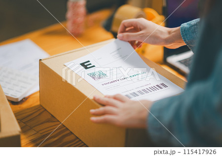 startup young female small business owners attaching shipping labels to cardboard boxes or parcels for delivery of customer orders-concept shopping online. 115417926