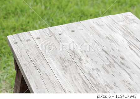 芝生背景にヴィンテージな木目のテーブル。キャンプやアウトドアイメージのディスプレイ 芝生背景にヴィンテージな木目のテーブル。キャンプやアウトドアイメージのディスプレイ 115417945