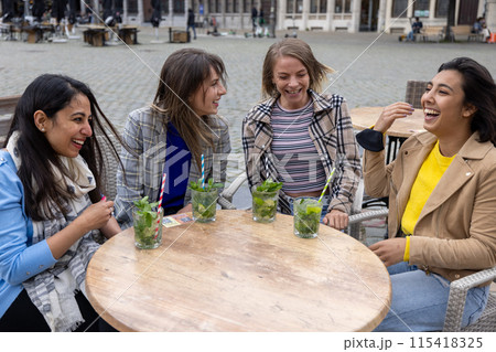 A group of friends are having a great time sipping drinks outdoors in a busy city setting A group of friends are having a great time sipping drinks outdoors in a busy city setting 115418325