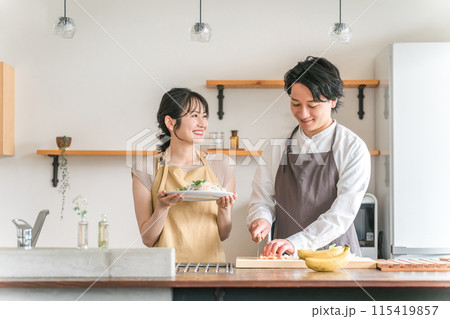 キッチンで料理をする夫婦・包丁で野菜を切る男性 115419857