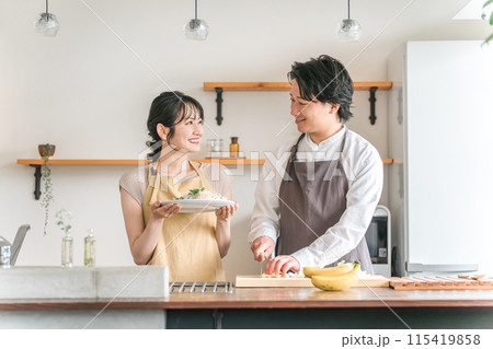 キッチンで料理をする夫婦・包丁で野菜を切る男性 115419858