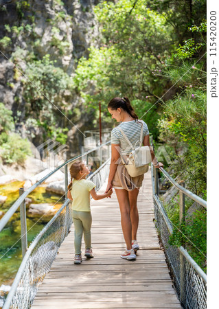 Mother with little girl hiking in Sapadere canyon with wooden paths and cascades of waterfalls in the Taurus mountains, Turkey. Eco tourism concept Mother with little girl hiking in Sapadere canyon with wooden paths and cascades of waterfalls in the Taurus mountains, Turkey. Eco tourism concept 115420200